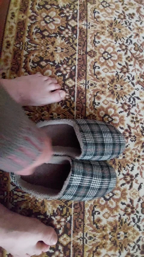Close up of feet stepping into slippers on patterned rug Stock Footage 334850114