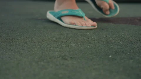 Close up of feet in turquoise flip flops walking on green textured floor showing Stock Footage 345974106