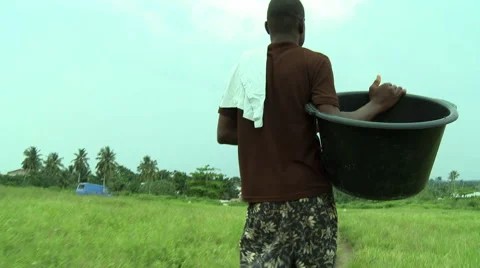 CLOSE UP OF FEET WALKING DOWN TRAIL TILIT UP TO MAN CARRYING WATER BUCKET Stock Footage 58069864