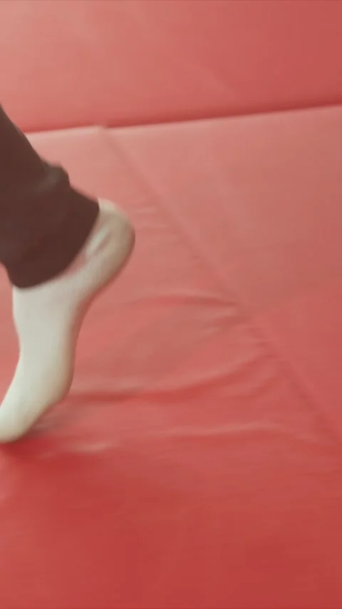 Close up of feet walking on red padded floor with dark pants and white socks Stock Footage 345545563