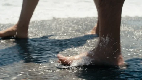 Close up feet walking through waves on beach Stock Footage 89999180