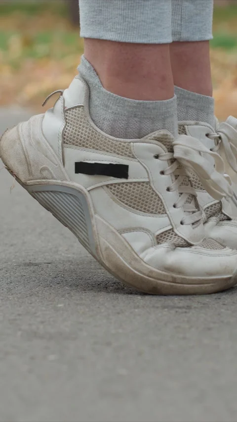 Close up of feet wearing white mesh and suede sneakers with scuff marks standing Stock Footage 345542897
