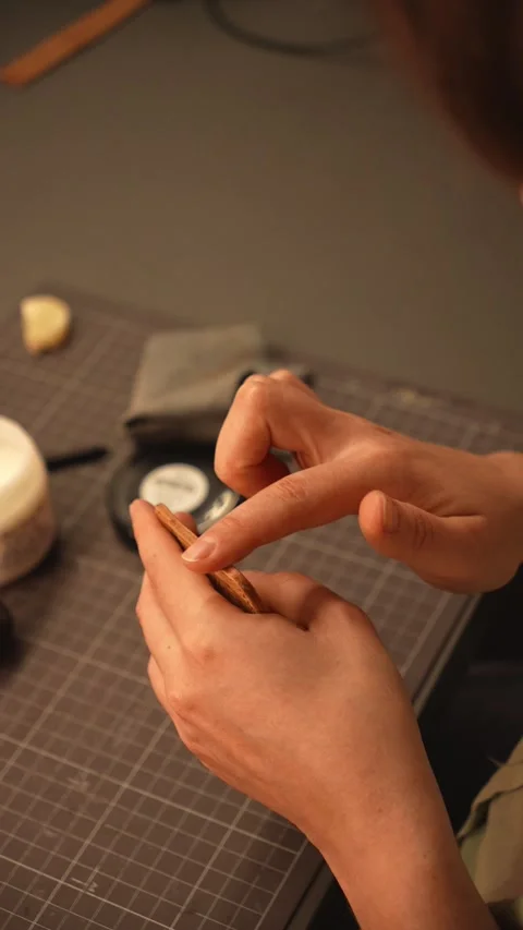Close-up of a female artisan applying edge finishing compound with her finger to Stock Footage 345975134