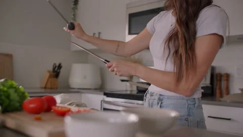 Close up of female chef sharpening knife in kitchen Stock Footage 220753830