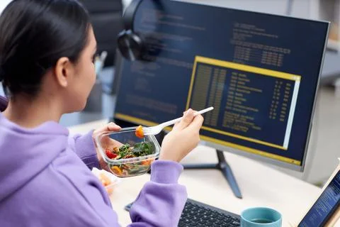 Close up of female computer programmer eating takeout lunch at workplace 写真素材