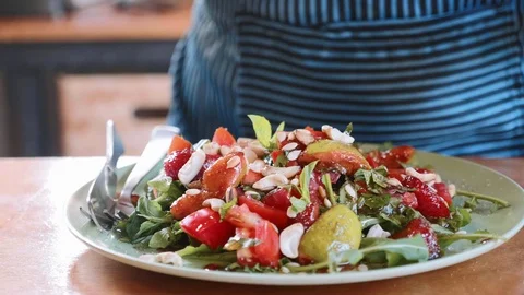 Close-up of female cook serving exotic sweet salad with vegetables and fruits Stock Footage 100589616