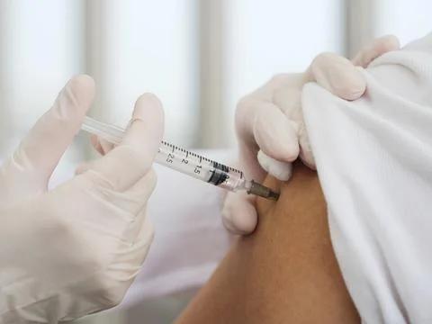 A close-up of a female doctor's hand using a syringe and cotton to vaccinate Stock Photos