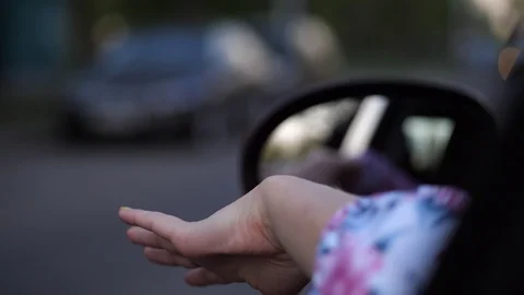 Close-up. A female driver during a trip stuck her hand out and makes waves Stock Footage 107828621