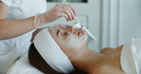 Close up of female face getting healthy clay mask by beautician Stock Footage 197174352