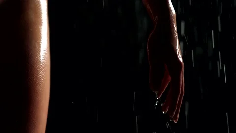 Close-up of a female hand on a black background in the rain. drops run off the Stock-Footage 206630232