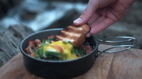 Close up of female hand dips bread in yolk and shows on background wild river Stock Footage 271552435