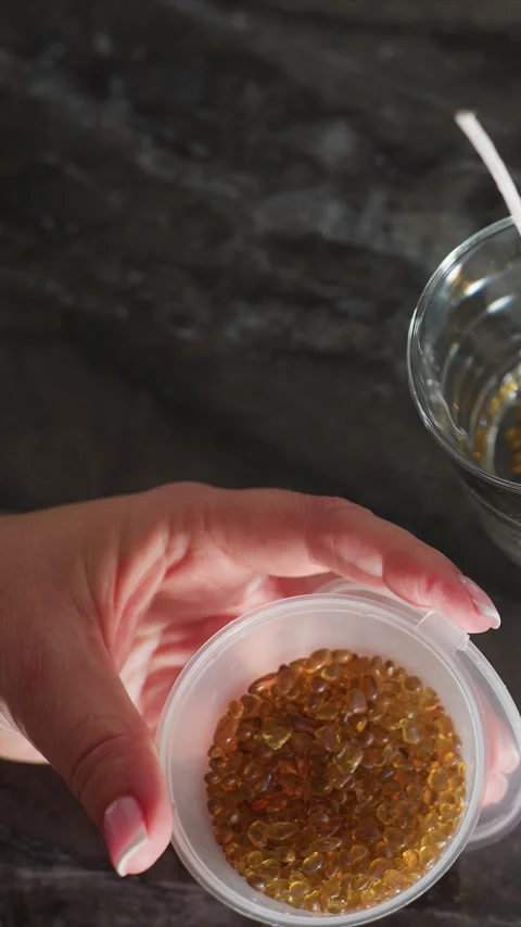 Close up of female hand holding small plastic container filled with amber Stock Footage 344677150
