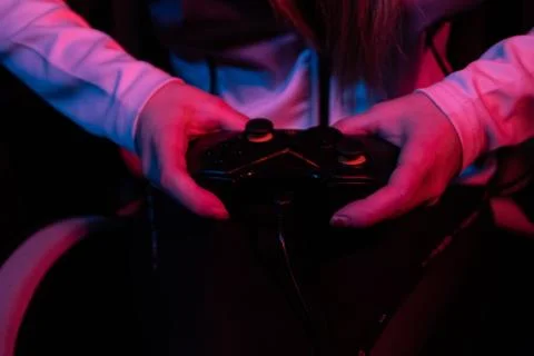 Close up of a female hand holding a video game controller in a room with pink Stock Photos