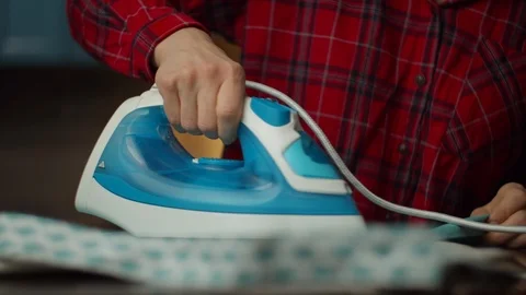 Close up of female hand ironing clothes with blue iron in slow motion.  Stock Footage