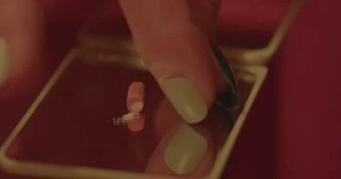 Close up of a female hand placing an open Oxycontin capsule with a little Stock Footage 281097917