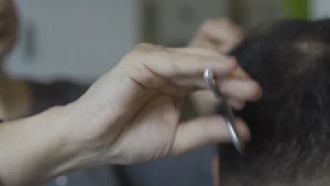 Close-up on a female hand with scissors that cut a man at home during the Stock Footage 130150245