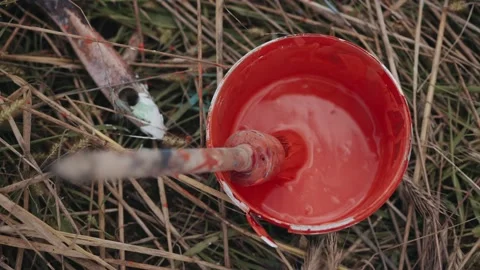 Close up of female hand soiled in paint dips a brush into a jar of red paint on Stock-Footage 165224979