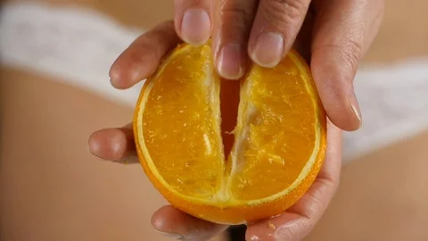 Close-up female hand stroking orange fruit imprinting a petting. imitation sex Stockbeeldmateriaal 92018257
