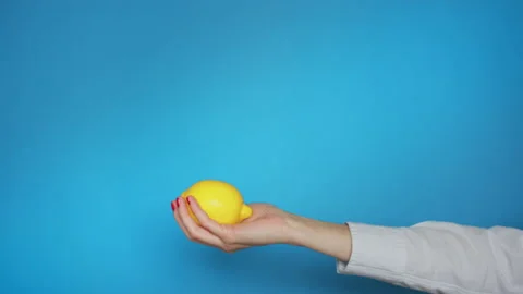 Close up female hand throwing fresh lemon up and catching in blue background Stock-Footage 136631982