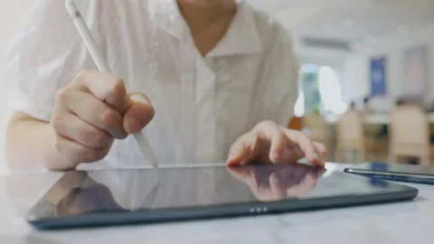 Close up of a female hand using digital tablet with a pen while working . Lif Stock Footage 241464562