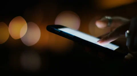 Close up on female hand using a phone at night with a blurred lights background Stock Footage 67736128