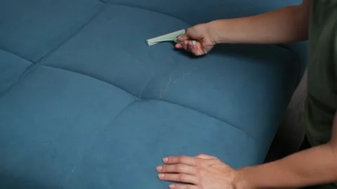 Close-up of female hand using an upholstery brush on a blue couch, scraping off Видео 316754786