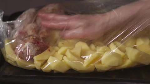 Close-up of Female Hands Adding Chicken Drumsticks and Potatoes to Roasting Bag 스톡 동영상 335229954