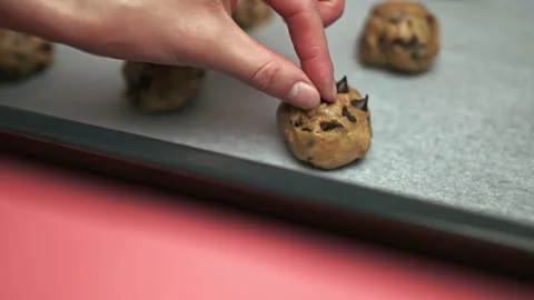 Close-up Female hands adding Chocolate Chips on top of Chocolate Chip Cookies. Stock Footage 135702289