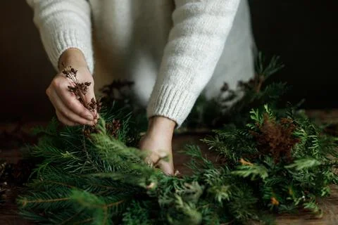 Close up of female hands adding dried plants into green fir Christmas wreat.. Stock Photos
