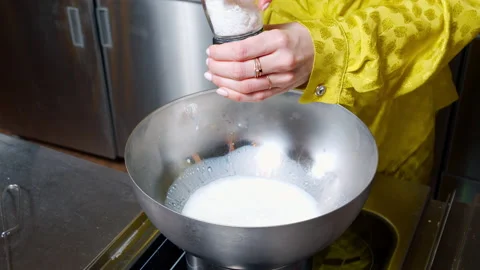 Close-up of female hands adding salt stirring with a whisk and checking the Stock Footage 154479658