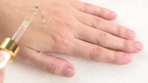 Close up female hands applying clear drop of essence or gel drops from the .. Stock Footage 284420439