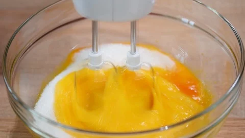 Close up of female hands beating egg yolks with sugar in a glass bowl on a Stock Footage 98796083