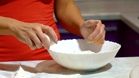 Close-up of female hands breaking an egg into pizza dough. Video stock 104127653