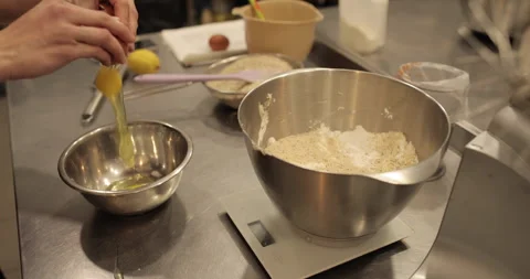 Close-up of female hands breaking an egg and adding Stock Footage 256410806