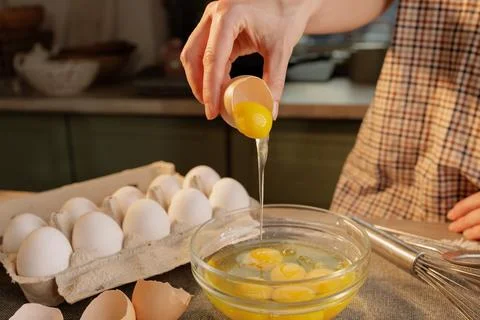 Close-up of female hands breaking an egg into a transparent bowl with eggs .. Stock Photos