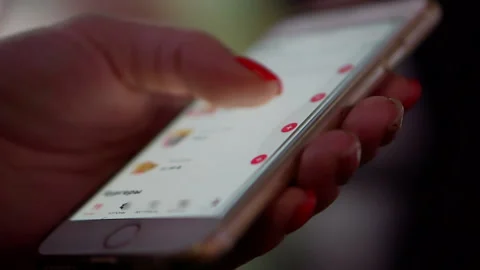 Close-up of female hands browsing an application on a smartphone in a cafe. Stock Footage 144025199