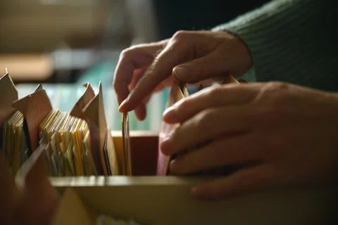 Close-up of female hands browsing old card catalog drawers, vintage library.. Stock Photos