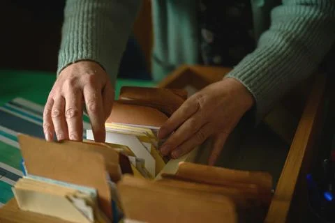Close-up of female hands browsing old card catalog in rustic wooden crate, .. Stock Photos