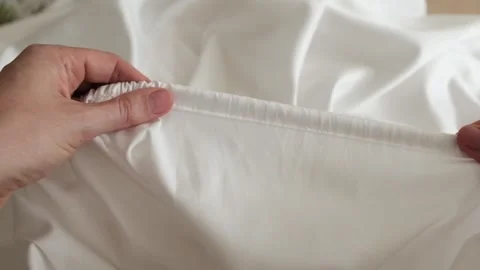Close up of female hands carefully assembles cotton fabric inserting a rubber Stock Footage 318482457