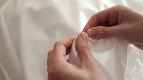 Close up of female hands carefully assembles cotton fabric inserting a rubber Stock Footage 318482531