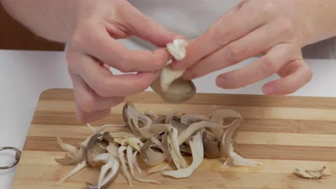 Close-up of female hands on a chopping board separating fresh mushrooms into Stock Footage 193380483