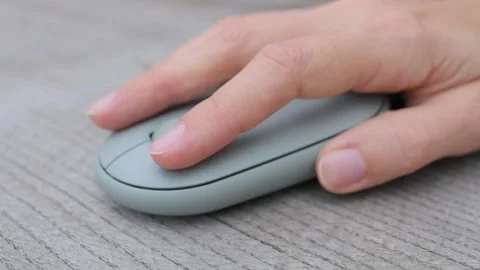 Close-up of female hands click on computer mouse on wooden table. Girl student Stockbeeldmateriaal 220018084