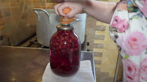 Close-up of female hands closing a glass jar with homemade cherry compote Stock Footage 333473006