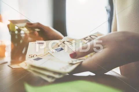Close up of female hands counting euro bills and using plastic debit card Stock Photos