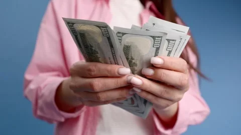 Close-up of female hands counting stack of hundred dollar bills blue background Stock Footage 241970831