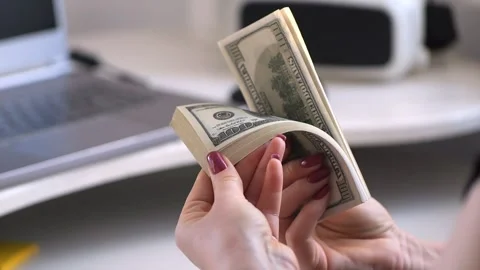 Close-up of female hands counting a stack of hundred-dollar US banknotes. a Stock Footage 266262202