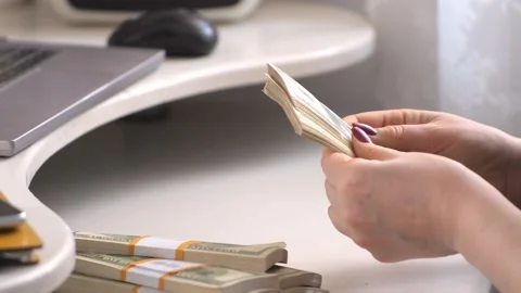Close-up of female hands counting a stack of hundred-dollar US banknotes. a Stock Footage 266422198