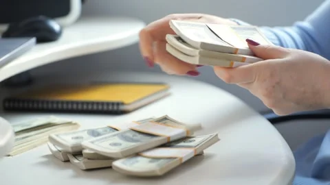 Close-up of female hands counting a stack of hundred-dollar US banknotes. a Stock Footage 267789431