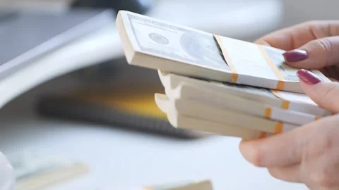 Close-up of female hands counting a stack of hundred-dollar US banknotes. a Stock Footage 269524004