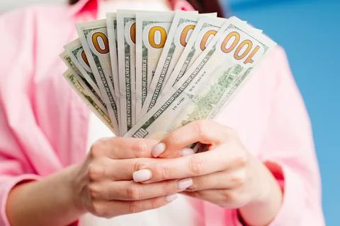 Close-up of female hands counting stack of hundred dollar bills blue backgrou Stock Photos
